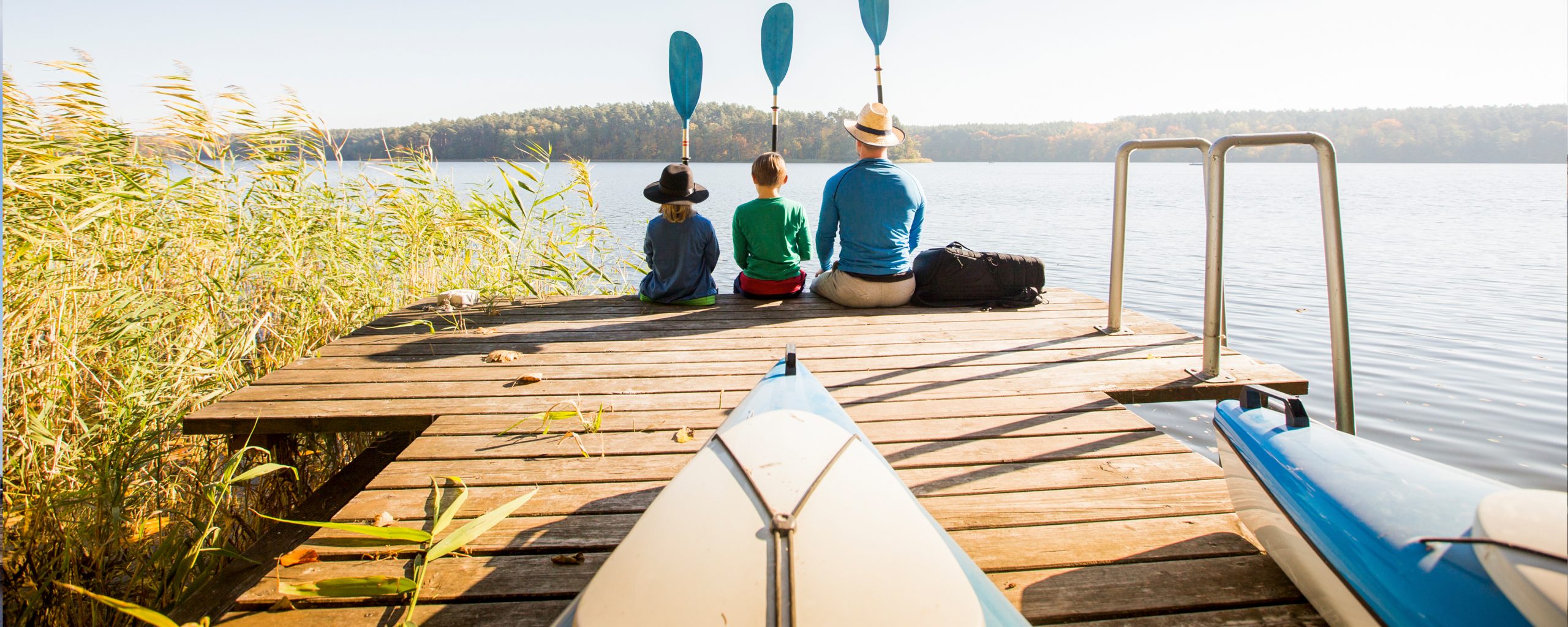 Two people with paddles at the end of a dock on a Michigan lake